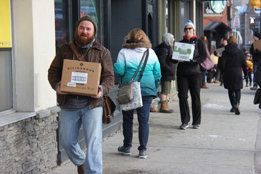 Kevin Heslop, one of close to 50 people who on Monday volunteered to help move London’s Brown & Dickson Book Shop to a new location, carries a box filled with books along Richmond Street. (JONATHAN JUHA, The London Free Press)