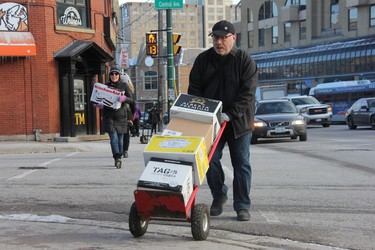 Bob Klanac transports a few boxes filled with books across the Central Avenue in downtown London. He was one of close to 50 people who on Monday volunteered their time to help a local bookstore move to a new location. (JONATHAN JUHA, The London Free Press)