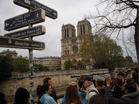 Onlookers watch Notre Dame Cathedral in Paris on Tuesday. Firefighters fought a more than 12-hour battle to extinguish an inferno engulfing Paris' iconic cathedral that claimed its spire and roof, but spared its bell towers and the purported Crown of Christ.