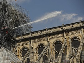 Firefighters work with a hose at the Notre Dame Cathedral in Paris, Wednesday, April 17, 2019. Donations have poured in for the vast restoration of the fire-ravaged Notre Dame cathedral, but a pledge by French President Emmanuel Macron that it will be completed within five years is facing accusations of being wildly off track. (AP Photo/Francisco Seco)