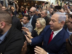 Israeli Prime Minister Benjamin Netanyahu, right, escorted by bodyguards walks with his wife Sara Netanyahu during a visit to the market on the eve of Israel's general elections in Jerusalem, Monday, April 8, 2019. (AP Photo/Sebastian Scheiner) ORG XMIT: SEB105