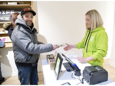 Jason Geldhof pays Jaimee Spada for the first legal purchase of marijuana in the history of London, Ont. on Monday April 1, 2019. Geldhof drove 80 minutes from his home in Goderich to be the first person in line at Central Cannabis, a store which began selling marijuana and related products today. Geldhof plans to frame his historic receipt.  (Derek Ruttan/The London Free Press)