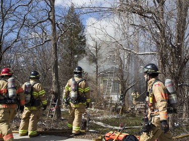 London firefighters extinguish a fire Monday at 458 Commissioners Rd. W. that caused an estimated $450,000 in damage. A passing firefighter saw the flames through the tree cover and called crews. The homeowner and sole occupant returned while crews were on scene. (DEREK RUTTAN, The London Free Press)