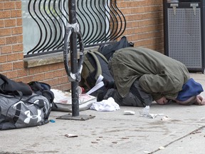An incapacitated man lies crumpled on the sidewalk in front of the Salvations Army's Centre of Hope in London, Ont. on Friday April 5, 2019. He and a woman ingested what police said was likely fentanyl, leading to the woman overdosing. The woman was revived with naloxone, an overdose antidote, administered by fellow clients of the facility. After being examined by paramedics the woman refused to go to hospital and was released at the scene. The man eventually rose to his feet with help from Centre of Hope staff. Derek Ruttan/The London Free Press/Postmedia Network