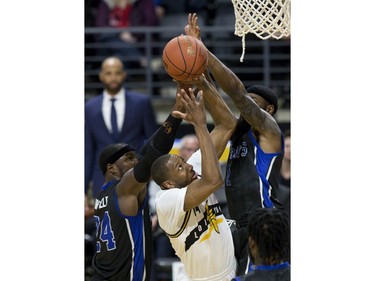 Marcus Capers of the London Lightning tries to get the ball through the arms of Flen Whitfield, left, and Ashton Smith of the Kitchener Waterloo Titans  during their NBL playoff game in London Tuesday April 9, 2019. Derek Ruttan/The London Free Press