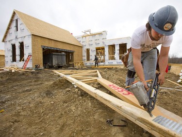 Nick Johnston of Under R construction company nails together two roof trusses that will hold a large load near the centre of the home the company is framing in the new construction site south of Pack Road just west of Colonel Talbot Road in London.  (Mike Hensen/The London Free Press)