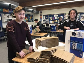 London Christian High Grade 12 students Lancer Cai, left, and Brandon Peng fold donation bags for the London Food Bank spring food drive, a 32nd annual tradition for the east London school. Donation bags will be distributed in the April 18 edition of The London Free Press. (Jennifer Bieman/The London Free Press)