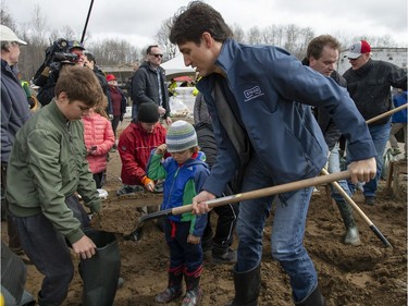 Prime Minister Justin Trudeau fills sandbags with his son Xavier, as son Hadrien watches, in Constance Bay on Saturday.