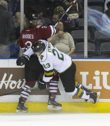 London Knights forward Drake Rymsha is sent airborne by Guelph Storm defenseman Kyle Rhodes during their OHL junior hockey game at Budweiser Gardens in London on Friday December 19, 2014. CRAIG GLOVER The London Free Press / QMI AGENCY