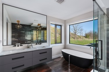 The master bathroom features a large mirror and big-window views of the surrounding area.