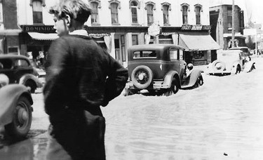 An unidentified young man watches as vehicles wade through flood waters on Thames Street in Chatham after a massive flood hit the area in April 1937. (Handout)