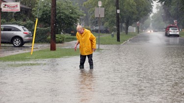 Windsor, Ontario. August 29, 2017.  Heavy rainfall caused many Riverside streets to flood Tuesday August 29, 2017. In photo, an unidentified man tries to unplug catch basin drain at Virginia Avenue at Wyandotte Street East.   (NICK BRANCACCIO/Windsor Star)