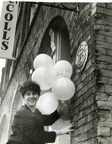 Ann McColl Lindsay holds Heritage Day balloons beside a plaque marking her building at 350 Talbot Street, as a heritage building, 1988. (London Free Press files)