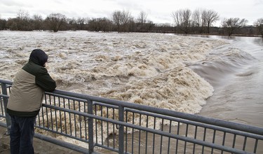 Onlookers watch the raging waters of the Grand River at Wilkes Dam in Brantford, Ontario on Wednesday afternoon. Rising water levels and ice moving on the river forced the City of Brantford to declare a state of emergency and order evacuation of residents in parts of the city. Brian Thompson/Brantford Expositor/Postmedia Network ORG XMIT: POS1802211723232004