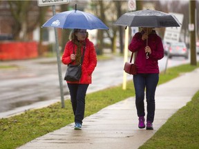 Cathy Foster and Linda Badke walk through the rain last month in south London. You might want to keep your umbrellas close at hand this morning. (MIKE HENSEN, The London Free Press)