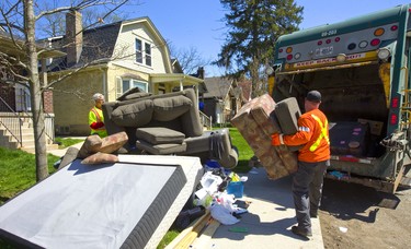 Jason Bailey hoists an armchair into a garbage truck on Huron Street in London, Ont.  Bailey and his partner Roland Sauer (lfeft)  were kept busy loading mattresses, bed frames, couches and ottomans into the hydralic maw of their truck. Fleeing Western students left their annual debris on the sides of London streets as the school year runs down in London, Ont.  Photograph taken on Thursday May 2, 2019.  Mike Hensen/The London Free Press/Postmedia Network Photograph taken on Thursday May 2, 2019.  Mike Hensen/The London Free Press/Postmedia Network
