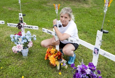 Lynn Pigeau embraces a cross bearing the name of her brother at a memorial for inmates that perished inside the Elgin Middlesex Detention Centre in London. (Derek Ruttan/The London Free Press)