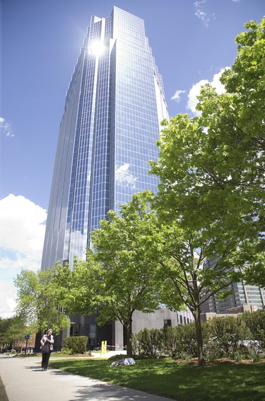 A man sleeps on the grass under One London Place, the city's tallest building and a beacon of commerce in London, Ont. on Thursday May 23, 2019. Derek Ruttan/The London Free Press/Postmedia Network