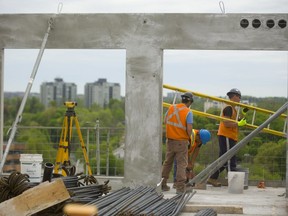 Helder Monez, using a drill, and Jonathan Camara brace a section of balcony wall while Marcello Ianni moves a ladder on the 10th floor of Tricar Group’s 24-storey Riverwalk residential tower being built on York Street just east of the Thames River in London.  (MIKE HENSEN, The London Free Press)