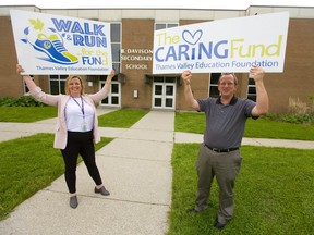 Jackie Ellefsen, the executive director of Thames Valley Education Fund and B. Davison principal Chris Friesen hold up signs for their fundraiser hoping to raise more awareness and funds for their work in supporting students in London, Ont.  (Mike Hensen/The London Free Press)