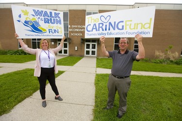 Jackie Ellefsen, the executive director of Thames Valley Education Fund and B. Davison principal Chris Friesen hold up signs for their fundraiser hoping to raise more awareness and funds for their work in supporting students in London, Ont.  (Mike Hensen/The London Free Press)