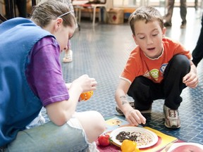 Morrison Jackson, 6, right, and volunteer Shalandra Wood, left, create fruit faces using peppers and seeds at the London Children's Museum.  The activity is part of the Grickle Grass Festival. (File photo)