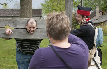 With his head and hands firmly in the stockade, Jason Green has his photo taken by his wife, Renee, while pledging allegiance to U.S. Presdient Madison with some prompting by Ben Brown of the 17th Kentucky Infantry at Fanshawe Pioneer Village in London on Sunday May 13, 2012.  The Village was the first stop on the 43rd annual London Free Press Shunpiker Mystery Tour.  The day-long tour took Shunpikers to 7 attractions, with the route beginning in London and ending in Goderich. (The London Free Press)