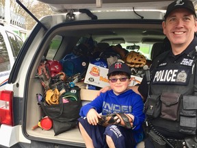 Maguire Smale, 9, and London police Const. Christopher Golder show off just some of the baseball gear collected for Rookie League baseball.
