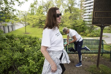 Toronto, ONT.: May 30, 2019 -- Rebecca McLean takes a break as Lynn Pigeau checks her phone and stretches and soothes her painful limbs on a bench along Dundas Street West near Scarlett Road, during their 184 km walk to bring changes to corrections. Toronto, Ont., May 30, 2019. (Nick Kozak for Postmedia News). ORG XMIT: POS1905301829200793
