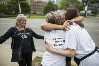 Toronto, ONT.: May 30, 2019 -- Tina McCool watches as Lynn Pigeau embraces Rebecca McLean and Lisa Hennessey following their arrival at Queen's Park thus completing their 184 kilometre walk from London to Toronto to bring changes to corrections in Ontario. Toronto, Ont., May 30, 2019. (Nick Kozak for Postmedia News). ORG XMIT: POS1905301829450799