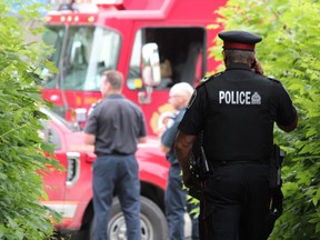 A police officer monitors the scene at Carfrae Crescent, south of Horton Street in London, where emergency crews pulled an unconscious man from the Thames River on Thursday. (DALE CARRUTHERS, The London Free Press)