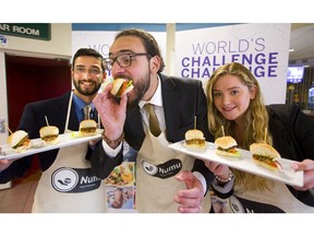 Abdulrahman Hassaballah bites into one of their “Numu” burgers served up by teammates Anish Kirtane and Olivia Burgner. (Mike Hensen/The London Free Press)