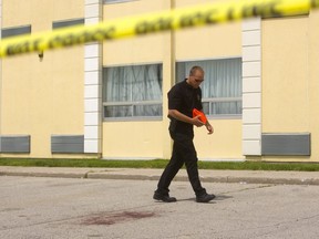 Forensic identification officer Paul Horenberg follows the blood trail that exits the Ramada Inn and ends with a large stain in the hotel parking lot after a man showed up in a London hospital with gunshot wounds June 17 in London. (Mike Hensen/The London Free Press)