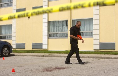 Forensic identification officer Paul Horenberg follows the blood trail that exits the Ramada Inn and ends with a large stain in the hotel parking lot after a man showed up in a London hospital with gunshot wounds Monday in London. (Mike Hensen/The London Free Press)