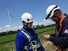 Kevin Aikenhead, left, facility manager for South Kent Wind, and Jamie Edwards, lead technician, prepare their safety harnesses at the wind farm, located southwest of Chatham. The 124-turbine project, owned by Pattern Energy and Samsung, became operational in 2014. (Trevor Terfloth/The Daily News)