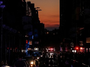 People walk along a dark street near Times Square area, as a blackout affects buildings and traffic during widespread power outages in the Manhattan borough of New York on July 13. (Jeenah Moon/Reuters)