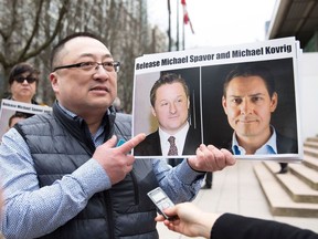 In this file photo taken on March 6, 2019, Louis Huang of Vancouver Freedom and Democracy for China holds photos of Canadians Michael Spavor and Michael Kovrig, who are being detained by China, in Vancouver, Canada.