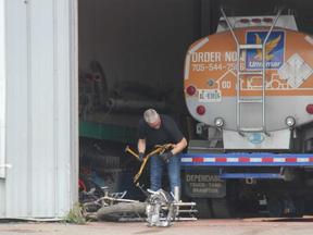 A London police officer is seen removing a motorcycle frame out of a garage at a business in the city's east end. The business, Robo Tech Fab Inc., was being searched Monday after police found a stolen motorcyle and a stolen pickup truck at the site the day before. JONATHAN JUHA/THE LONDON FREE PRESS