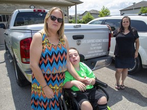 Leanne MacDonald, holding the hand of her 11 year old son Landon, needs a kidney transplant. She and six other friends and family members, including Michelle Bell at right, are spreading the message with decals on their vehicles. (Derek Ruttan/The London Free Press)