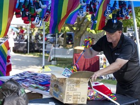 Clark Paton of Toronto sets up his flag and souvenir kiosk prior to the start of Pride In The Park festivities in Victoria Park Friday. (Derek Ruttan/The London Free Press)