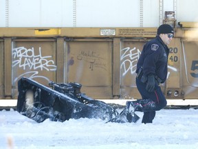 A police constable walks past part of a sidewalk snowplow that was struck by a CN train at the Colborne Street crossing in London on Jan. 9, 2018. (Free Press file photo)