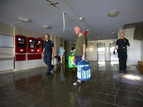 Tim Russell passes by emergency crews as he exits his apartment building at 940 Commissioners Rd. E. Wednesday after a large sprinkler pipe started flooding the building's first three floors.  (Mike Hensen/The London Free Press)