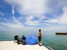 Brenden Fleming fishes for perch off the pier in Bayfield on a hot sunny summer day. Fleming had an umbrella set up for his wife Danielle with their four-month old son Myles, on his first fishing trip of the year, along with the grandparents, Sue and Scott Dinney of Crediton. Mike Hensen/The London Free Press/Postmedia Network