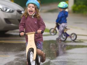 Oriah Baribeau, 4, with her brother Knox, 2, wouldn't let their parents Rylie Guest and Zach Baribeau even think about skipping their afternoon bike ride/walk in London after a rainfall. Guest and Baribeau swear by the advantages of so-called balance bikes that teach their kids balance before forcing them to learn how to pedal. (Mike Hensen/The London Free Press)