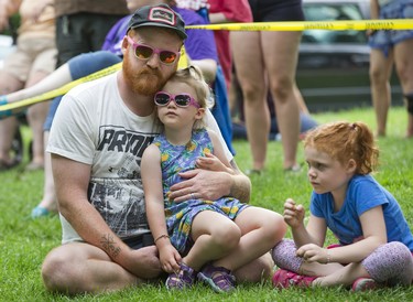 Matty Cusack and daughters Margie (3) and Rosie (6) listen to a performance by London Girls Rock Camp on the South Stage at the Home County Music and Art Festival in London, Ont. Derek Ruttan/The London Free Press/Postmedia Network