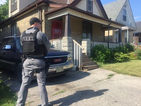 A London police officer stands outside 1026 Trafalgar St. following a raid on the home Wednesday. Two people were arrested, police said. DALE CARRUTHERS / THE LONDON FREE PRESS