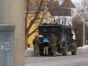Police officers escort a handcuffed suspect to vehicle after a nearly nine-hour standoff on Main Street in Listowel. (Crystal Kaiser/Special to the Beacon Herald)