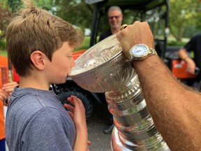 Will Meszaros drinks water from the Stanley Cup after Tim Taylor made a surprise visit with hockey's holy grail during a road hockey game in Stratford Thursday afternoon. Cory Smith/The Beacon Herald