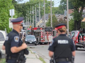 London police officers stand at Woodman Avenue and Dundas Street Thursday as firefighters probed the scene of a blast that levelled one home and damaged at least nine others.  (JONATHAN JUHA, The London Free Press)