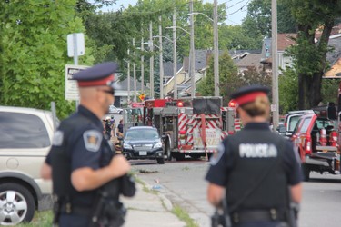London police officers stand at Woodman Avenue and Dundas Street as firefighters probed the scene of a blast that levelled one home and damaged at least nine others.  (JONATHAN JUHA, The London Free Press)